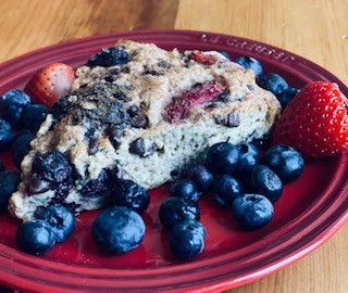 strawberry and blueberry scone on small red plate with sprinkling of fresh blueberries and strawberries