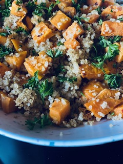 cubed sweet potatoes, quinoa, fresh parsley, in white speckled bowl