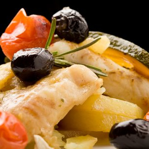 Four pieces of cod stacked crossing over each other with grape tomatoes, olives, and fresh rosemary garnish